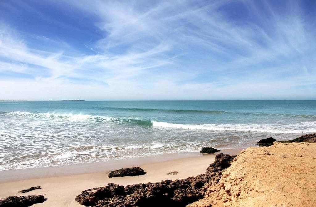 Plage de sable et rochers au bord de l'océan, sous un ciel bleu
